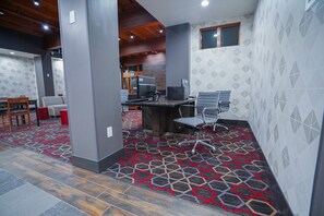 A modern office space with a patterned carpet, wooden ceiling beams, and a reception area with a computer and office chairs. - Four Points by Sheraton Salt Lake City Airport (Salt Lake City)
