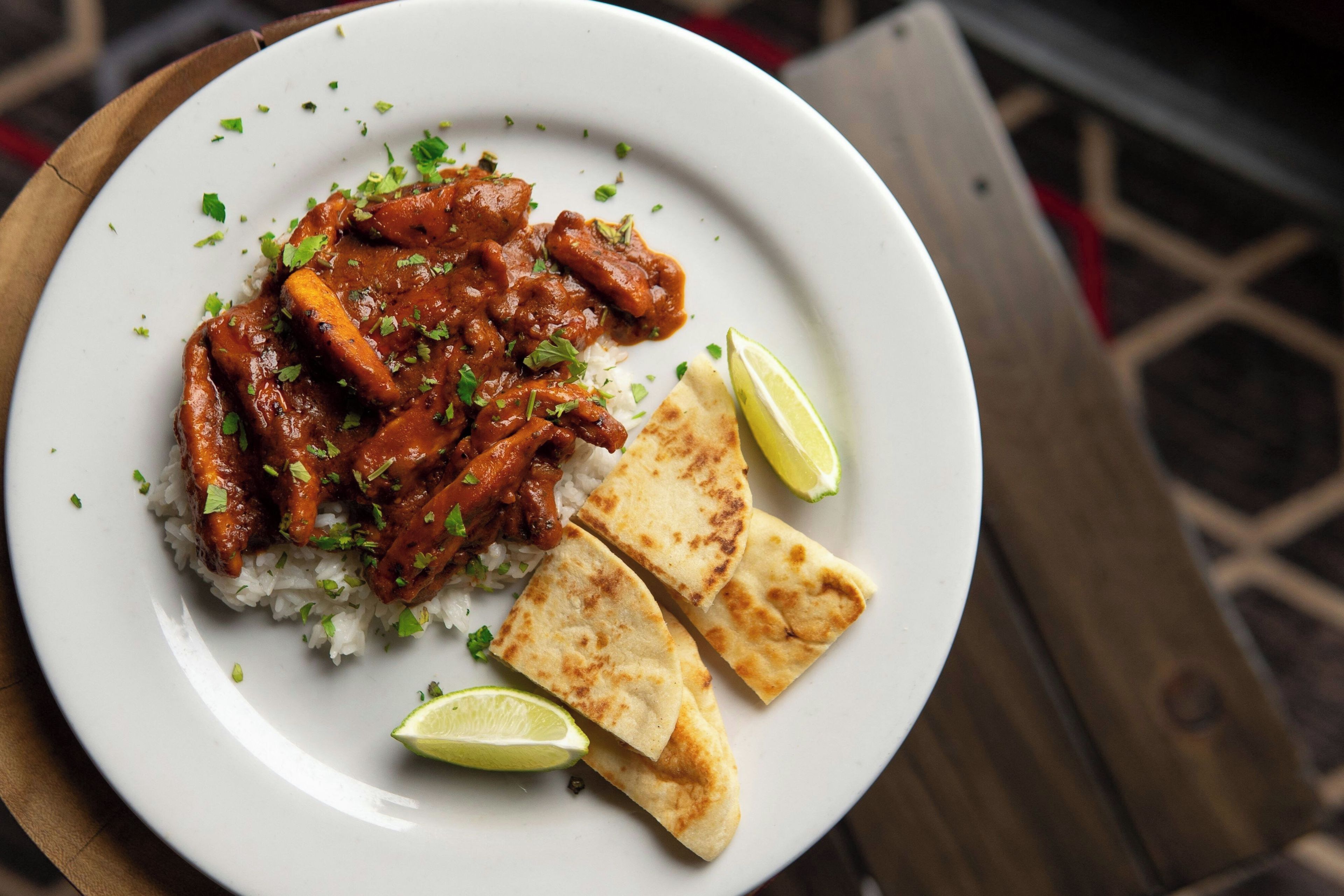 A plate of food with rice, meat, and flatbread, accompanied by a lime wedge.