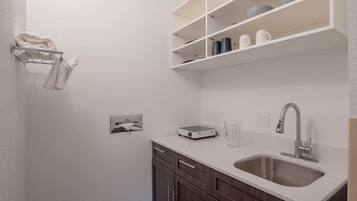 Una cocina moderna con encimera blanca, pileta de acero inoxidable y muebles de madera.