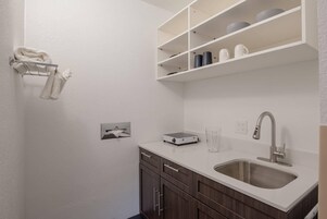 Una cocina moderna con encimera blanca, pileta de acero inoxidable y muebles de madera.
