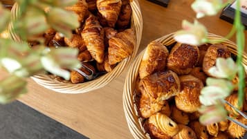 Deux paniers en osier remplis de diverses pâtisseries, posés sur une table en bois.
