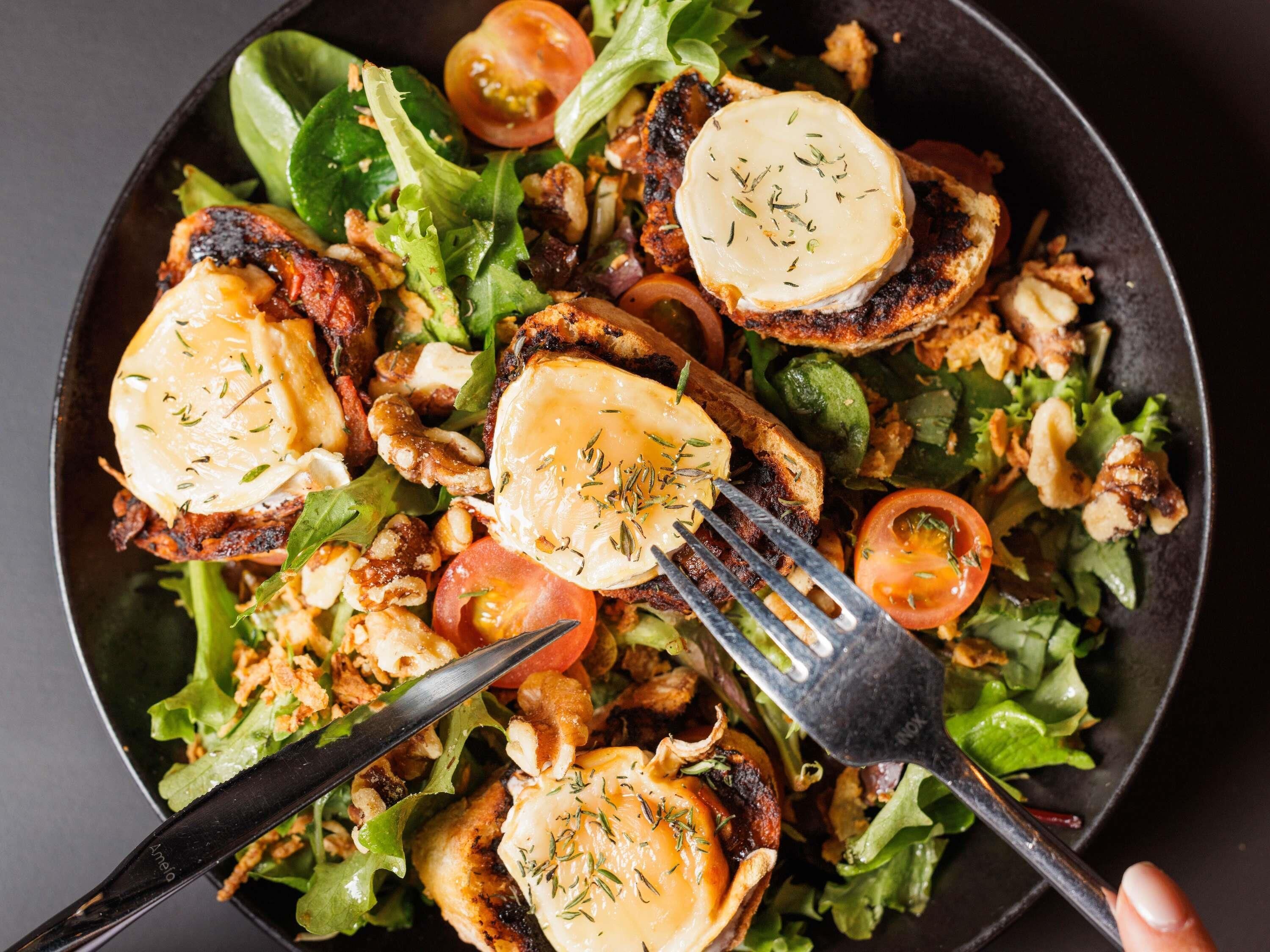 A salad with grilled chicken, cheese, and herbs.