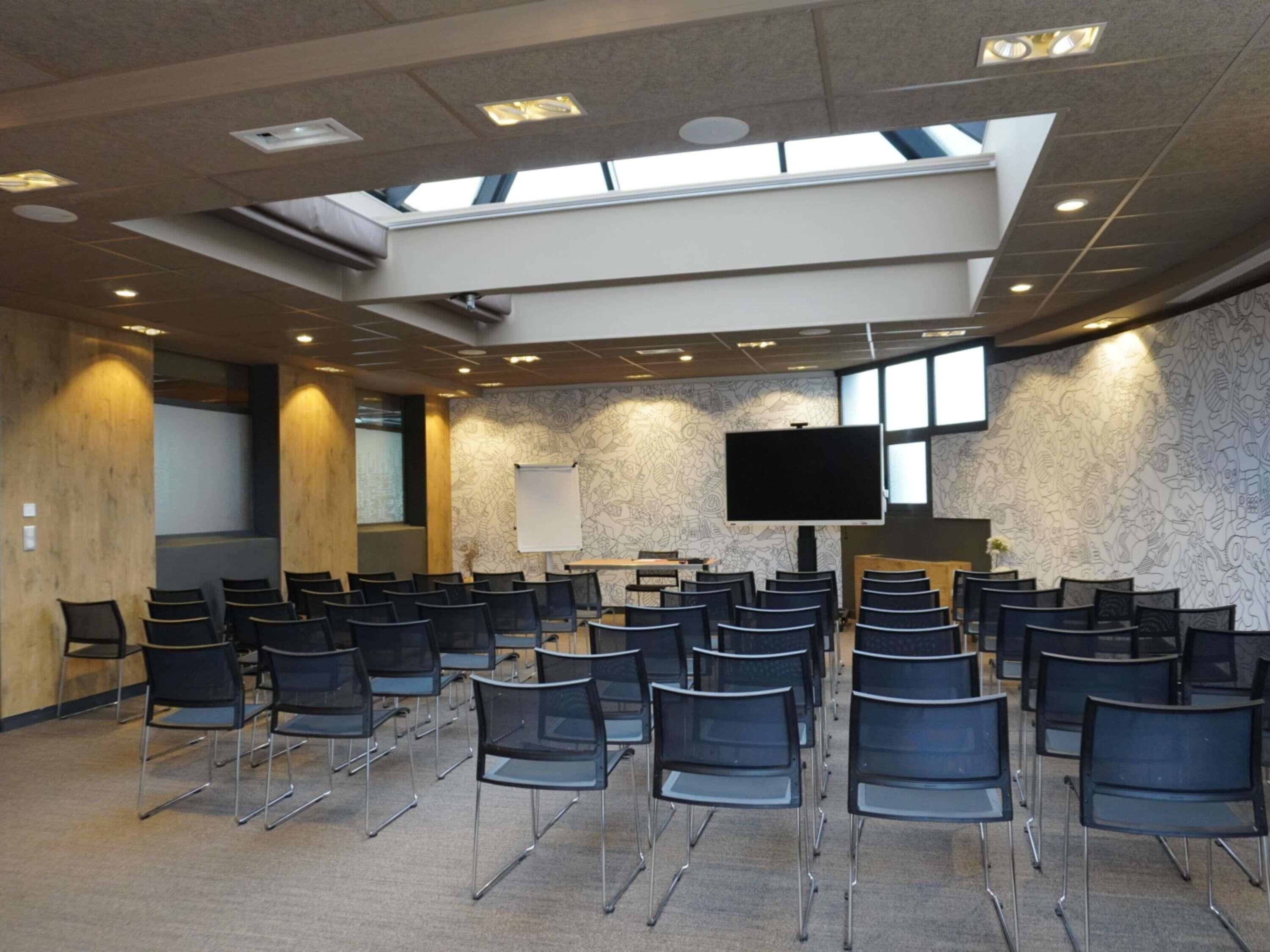 A conference room with rows of chairs, a large screen, and a whiteboard.