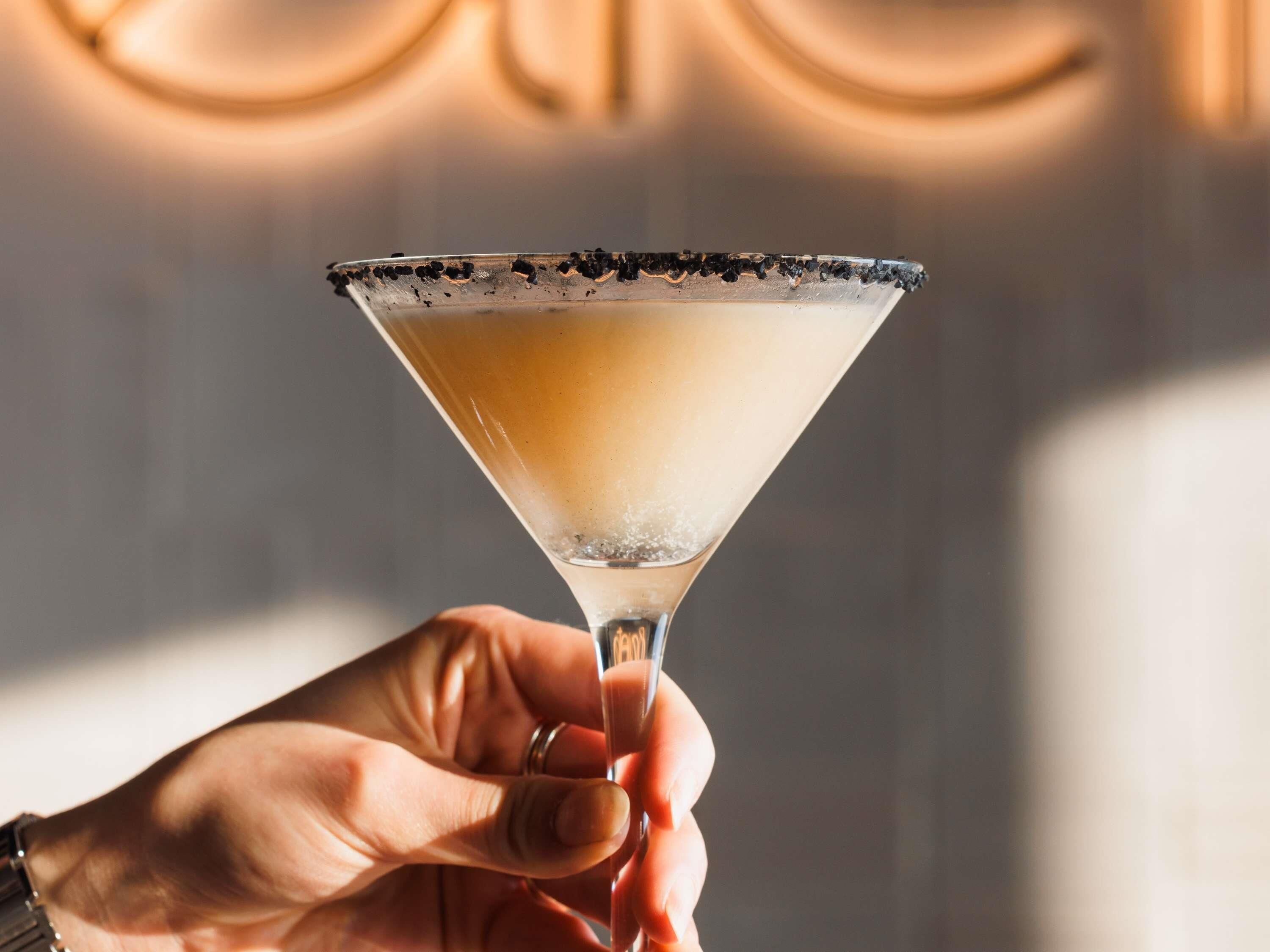 A hand holding a martini glass with a salted rim.
