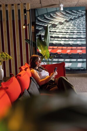 En person sidder på en rød og grå sofa og bruger en smartphone.