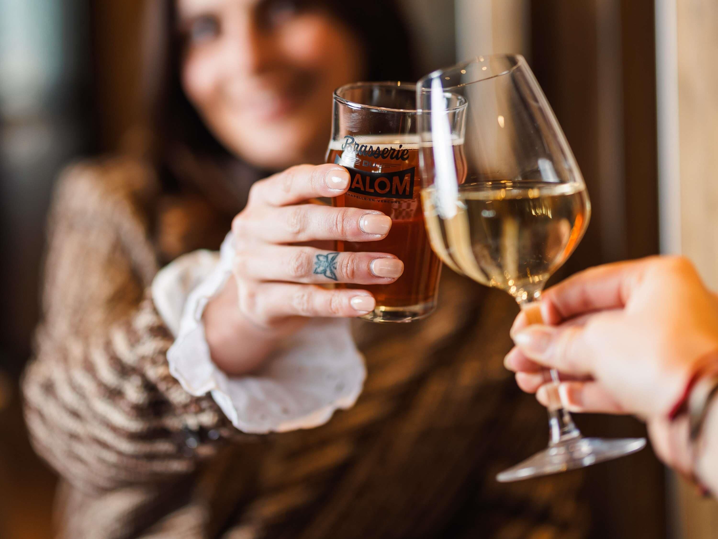 Zwei Personen halten Bier- und Weingläser.