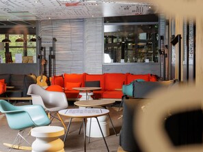 Un intérieur moderne avec un canapé rouge, des fauteuils turquoise et une guitare.