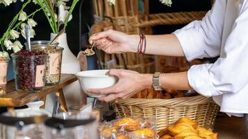 Una persona sirviendo comida de frascos, con una cesta de pasteles y un bol sobre una mesa.