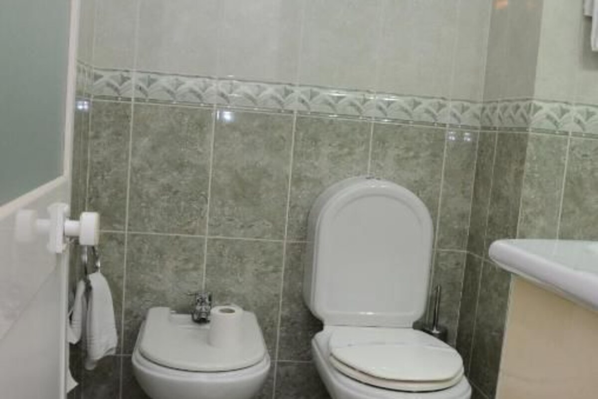 A bathroom with two toilets, a shower area, and a sink.