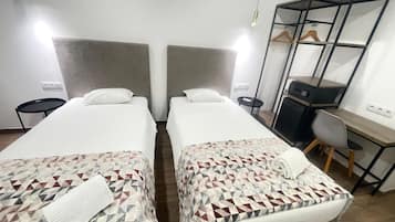 Ein Hotelzimmer mit zwei Betten, einem Schreibtisch, einem Stuhl, einem Kleiderschrank und einem kleinen Tisch.