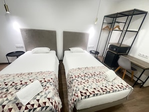 A hotel room with two beds, a desk, a chair, a wardrobe, and a small table. - Flamingo (Lisbon)