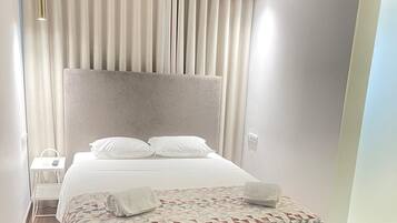 Une chambre d’hôtel moderne avec un grand lit, une table de chevet et une petite table d’appoint.