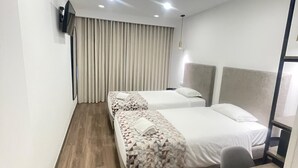 A hotel room with two beds, a desk, and a TV mounted on the wall. - Flamingo (Lisbon)