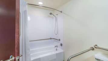 A bathroom with a shower, grab bars, and a toilet.