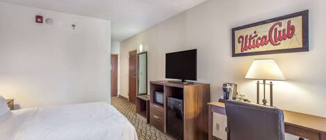 A hotel room with a bed, desk, TV, and a sign that reads "Utica Club".