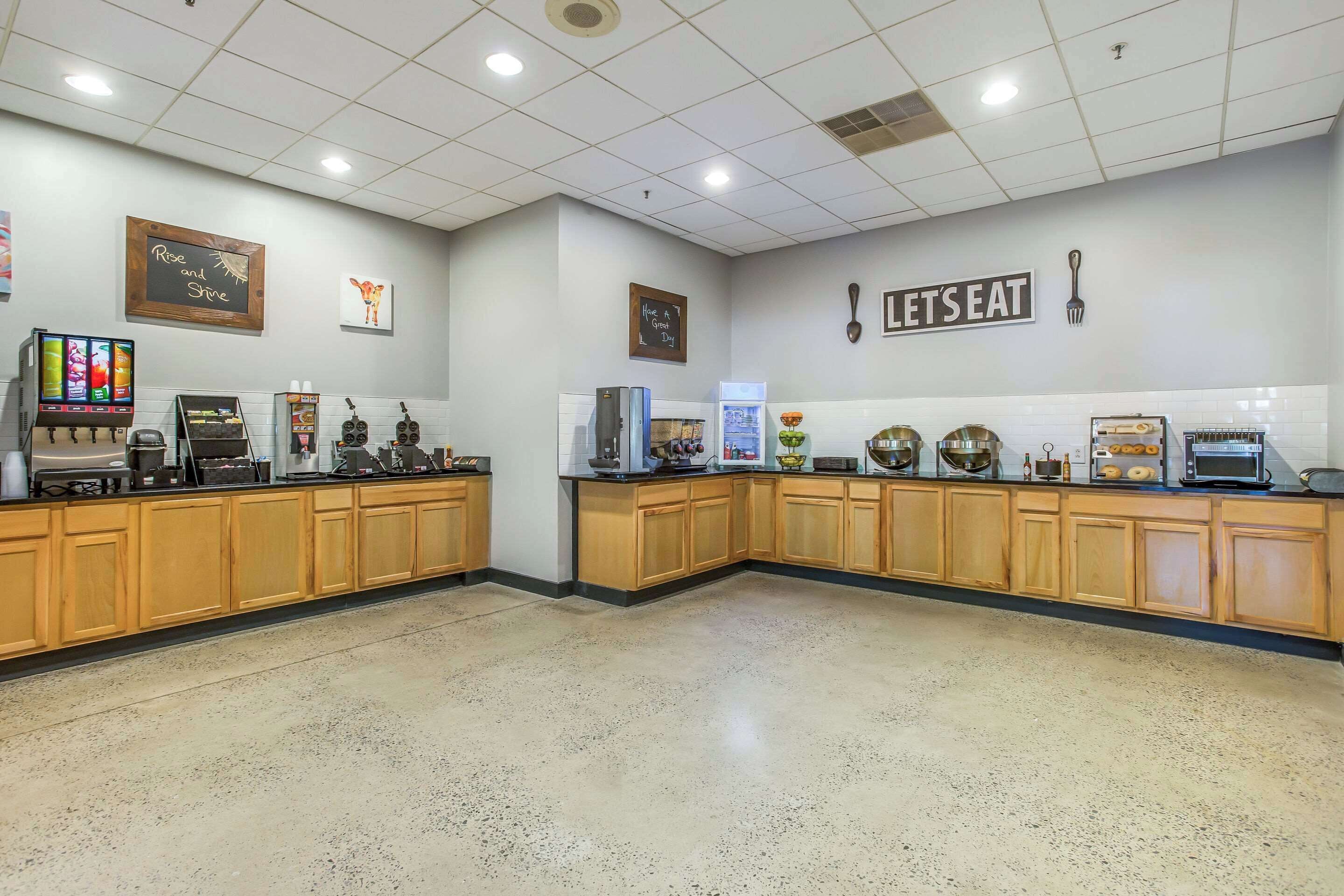 A spacious kitchen with wooden cabinets, a chalkboard with motivational writing, and various kitchen appliances.