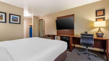 Habitación de hotel con una cama grande, un escritorio con computadora, un televisor y una lámpara.