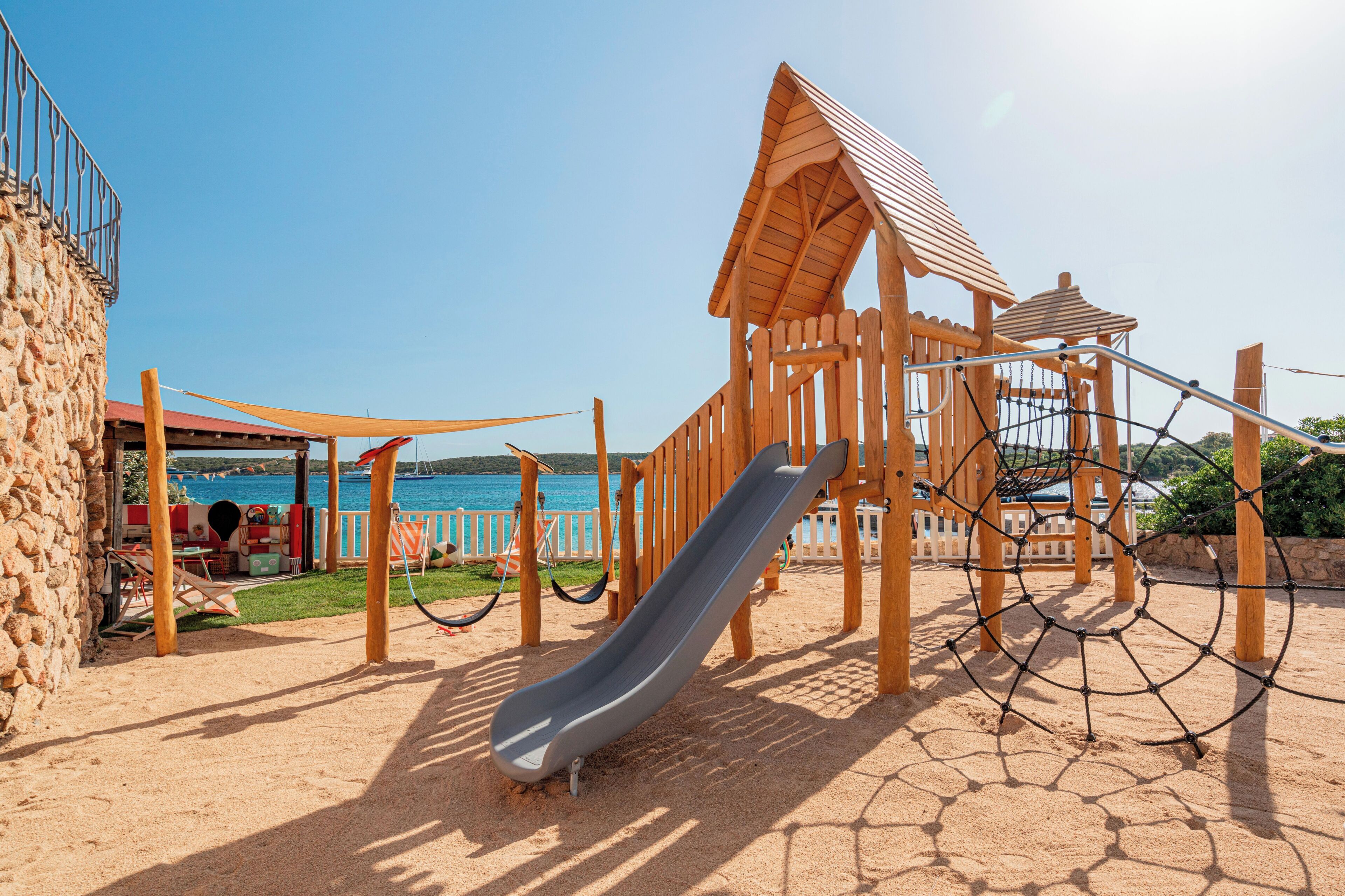 Un parque infantil con tobogán, columpios y una estructura para escalar.