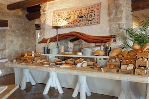 Una mesa de buffet con panes, pasteles y frutas variados.
