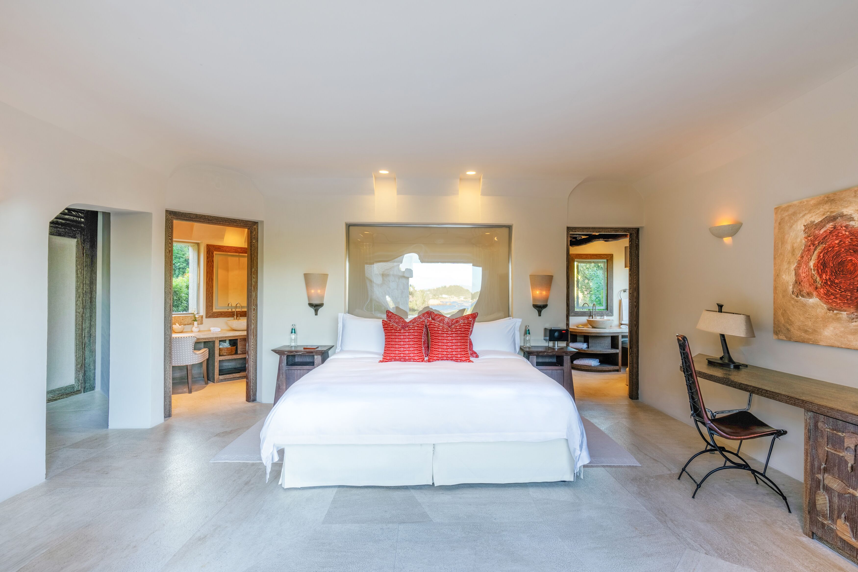 Ein geräumiges Schlafzimmer mit einem großen Bett, einem Schreibtisch mit Stuhl und einem durch eine offene Tür einsehbaren Badezimmer.