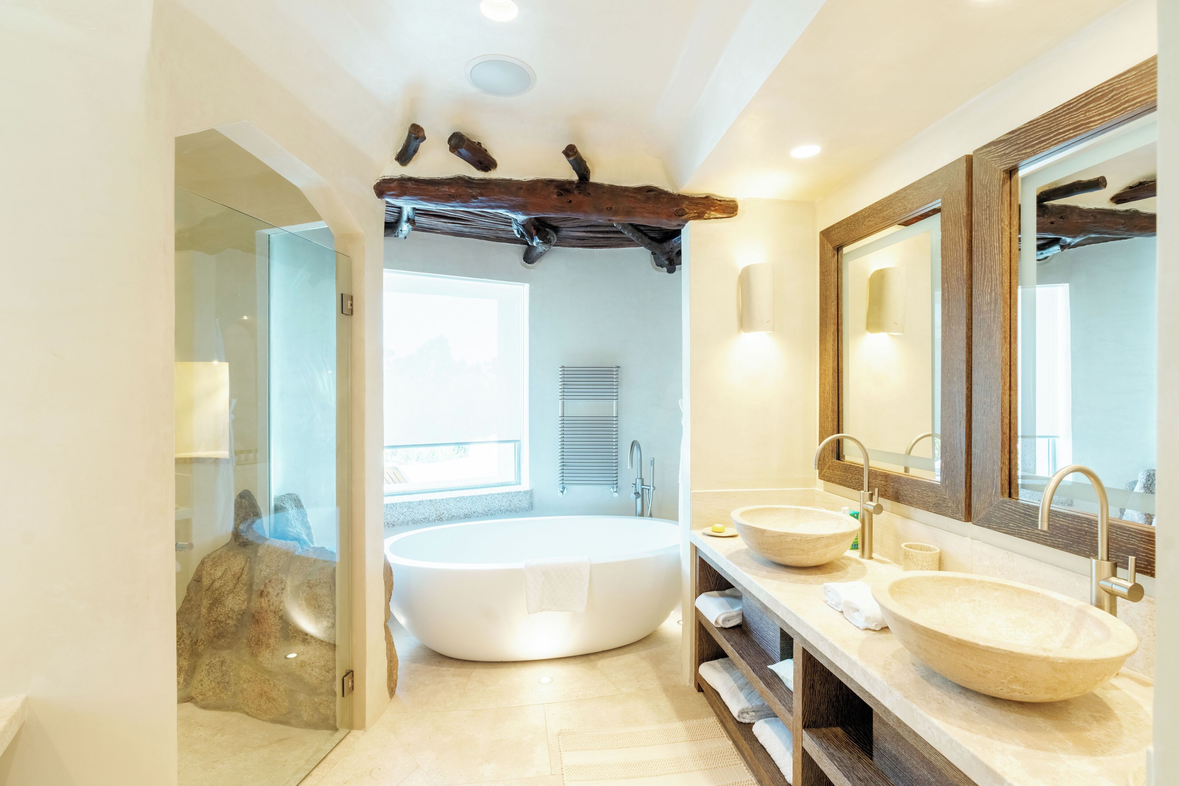 A modern bathroom with a freestanding bathtub, two sinks, and a large mirror.