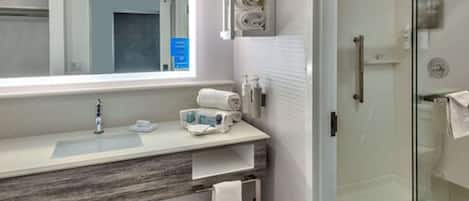 Un baño moderno con un espejo grande, un lavabo y una cabina de ducha de vidrio.