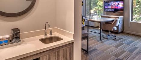 Un bany modern amb un mirall gran, un lavabo i un microones.