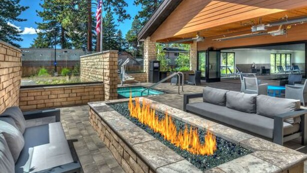 An outdoor patio with a fire feature, seating, and a pool.