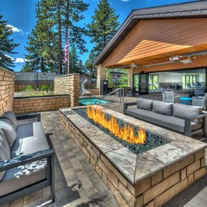 Un patio exterior con una chimenea, asientos y una piscina.