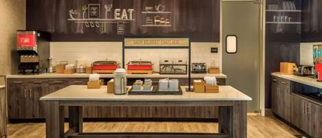 Cocina moderna con una isla central, armarios de madera y una pared oscura con un letrero que dice 'HEAT'.