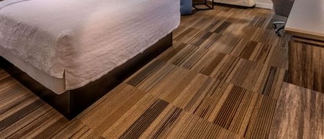 Una habitación de hotel moderna con una cama grande, un escritorio, una silla y una ventana con persianas.