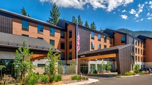 A modern multi-story hotel with a flat roof, large windows, and a covered entrance area.
