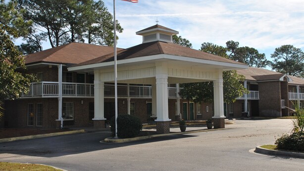 A two-story building with a covered entrance and a flagpole. - America's Best Inn and Suites Beaufort (Beaufort)