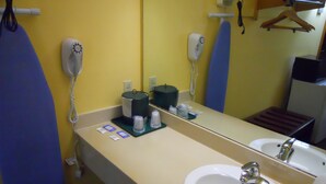 A hotel bathroom with a sink, mirror, and toiletries. - America's Best Inn and Suites Beaufort (Beaufort)