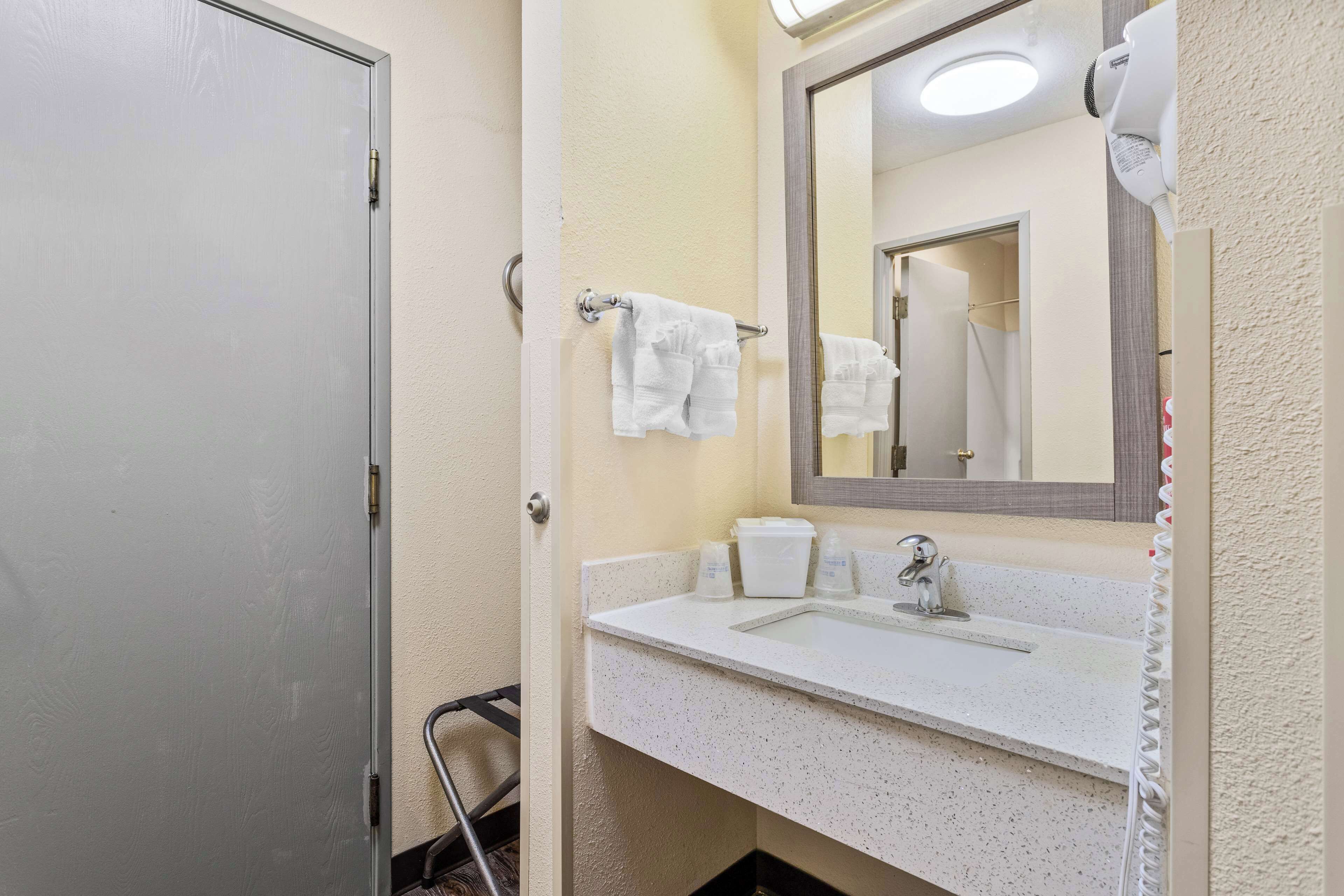 A bathroom with a white sink, a mirror, and a towel rack with two towels.