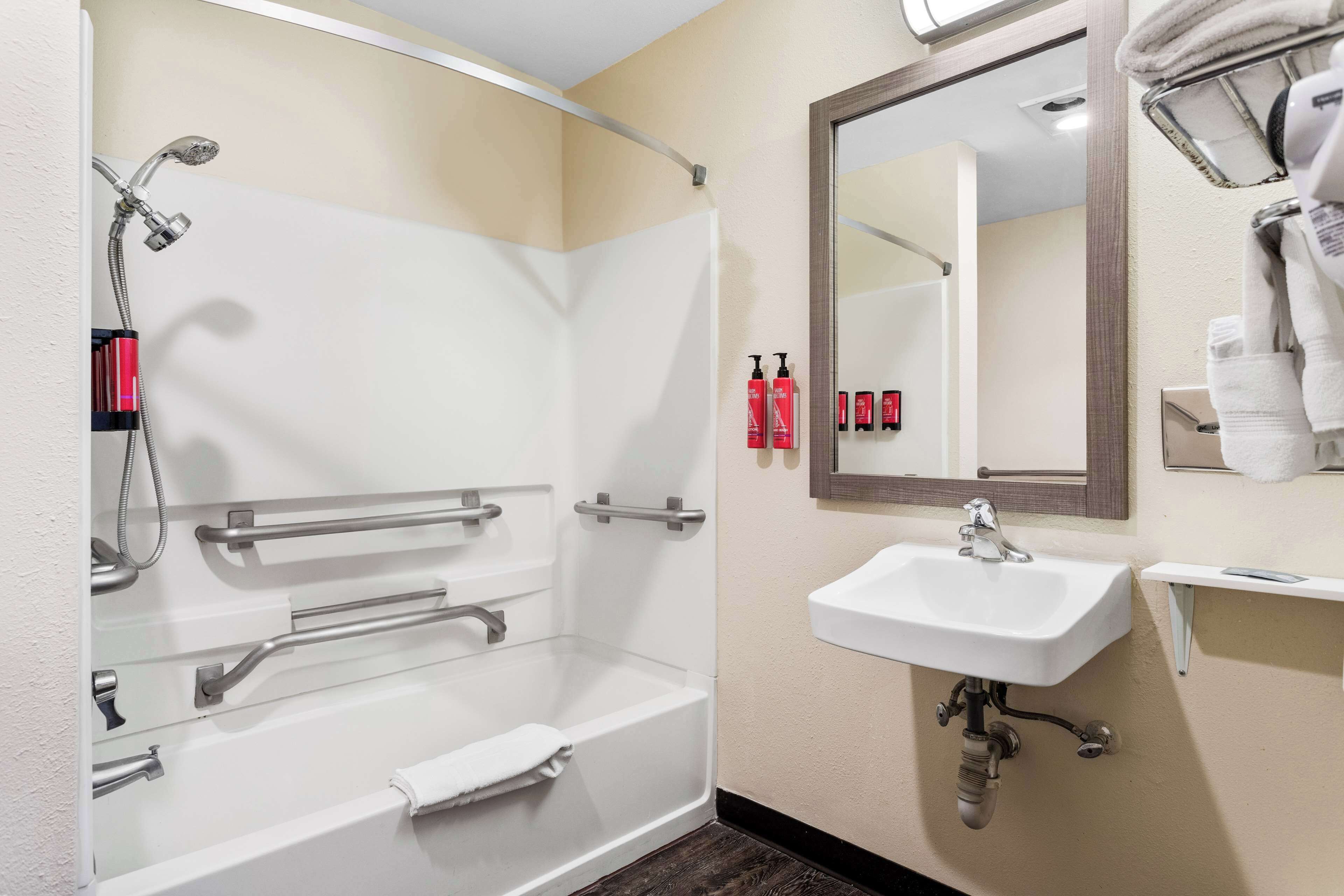 A bathroom with a bathtub, a sink, and a mirror.