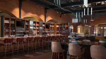 A bar area with multiple seating options, a bar counter, and a variety of bookshelves filled with books and bottles.