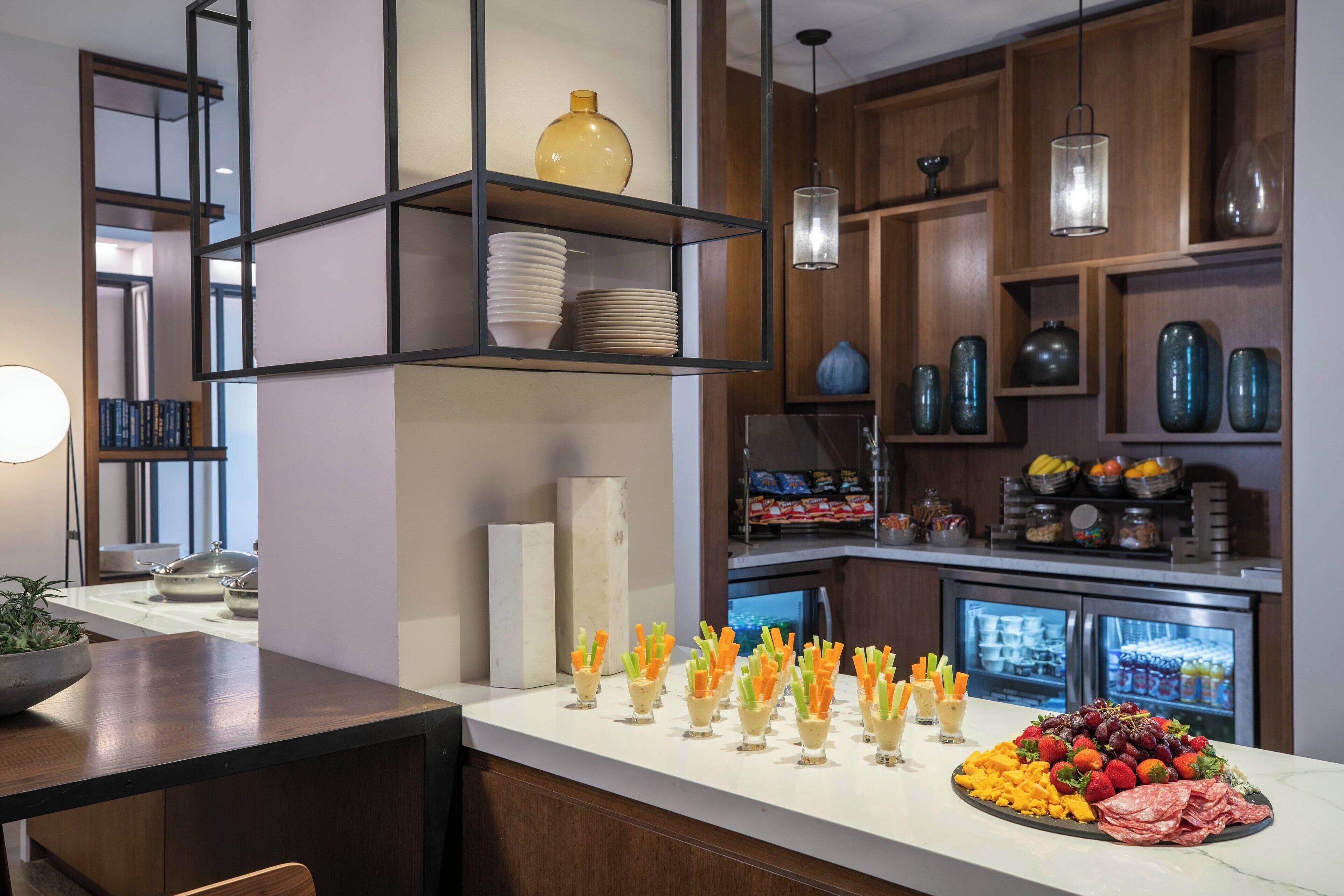 A well-organized kitchen with a buffet setup, including a variety of food items and neatly arranged glassware.