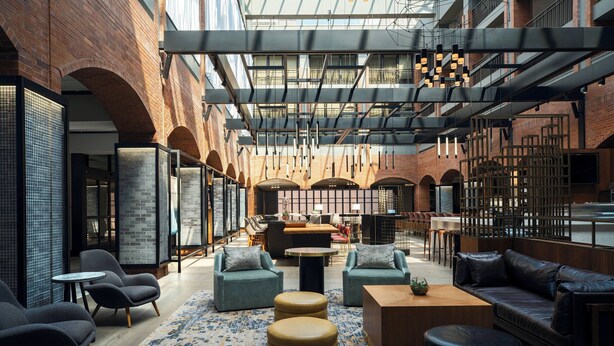 Een ruime lobby met modern meubilair, een kamerbreed tapijt en een hoog plafond met zichtbare balken.