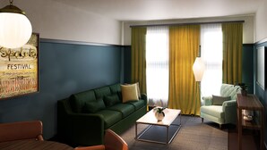 A living room with a green sofa, a coffee table, a lamp, and a painting on the wall.