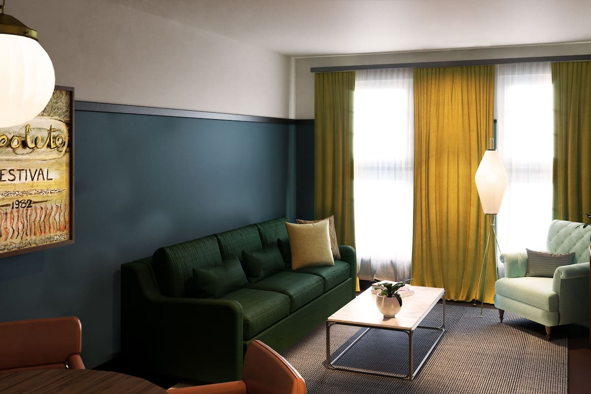 A living room with a green sofa, a coffee table, a lamp, and a painting on the wall.