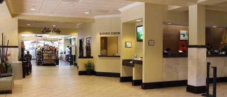 A hotel lobby with a business center, a convenience store, and a reception desk.