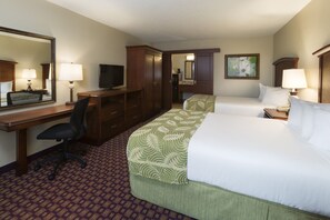 A hotel room with a bed, desk, chair, television, and a bathroom visible through an open door.