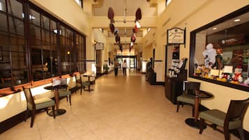 Un hall de hotel con una barra de café, zona de estar y vistas a la calle.