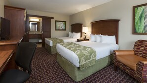 A hotel room with two beds, a desk, a chair, and a television.