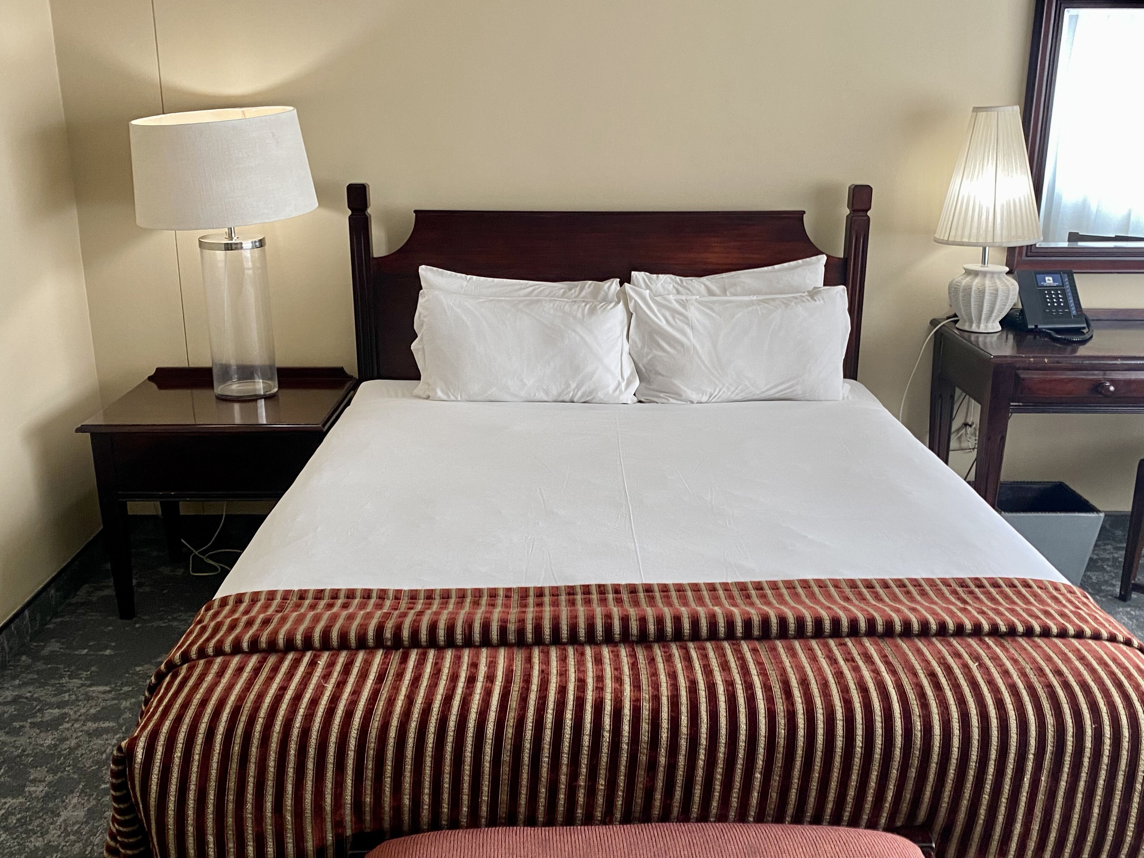 A hotel room with a large bed, two bedside tables, a lamp on each table, and a telephone on one of the tables.