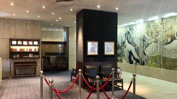 A lobby with a reception desk, seating area, and a mural on the wall.
