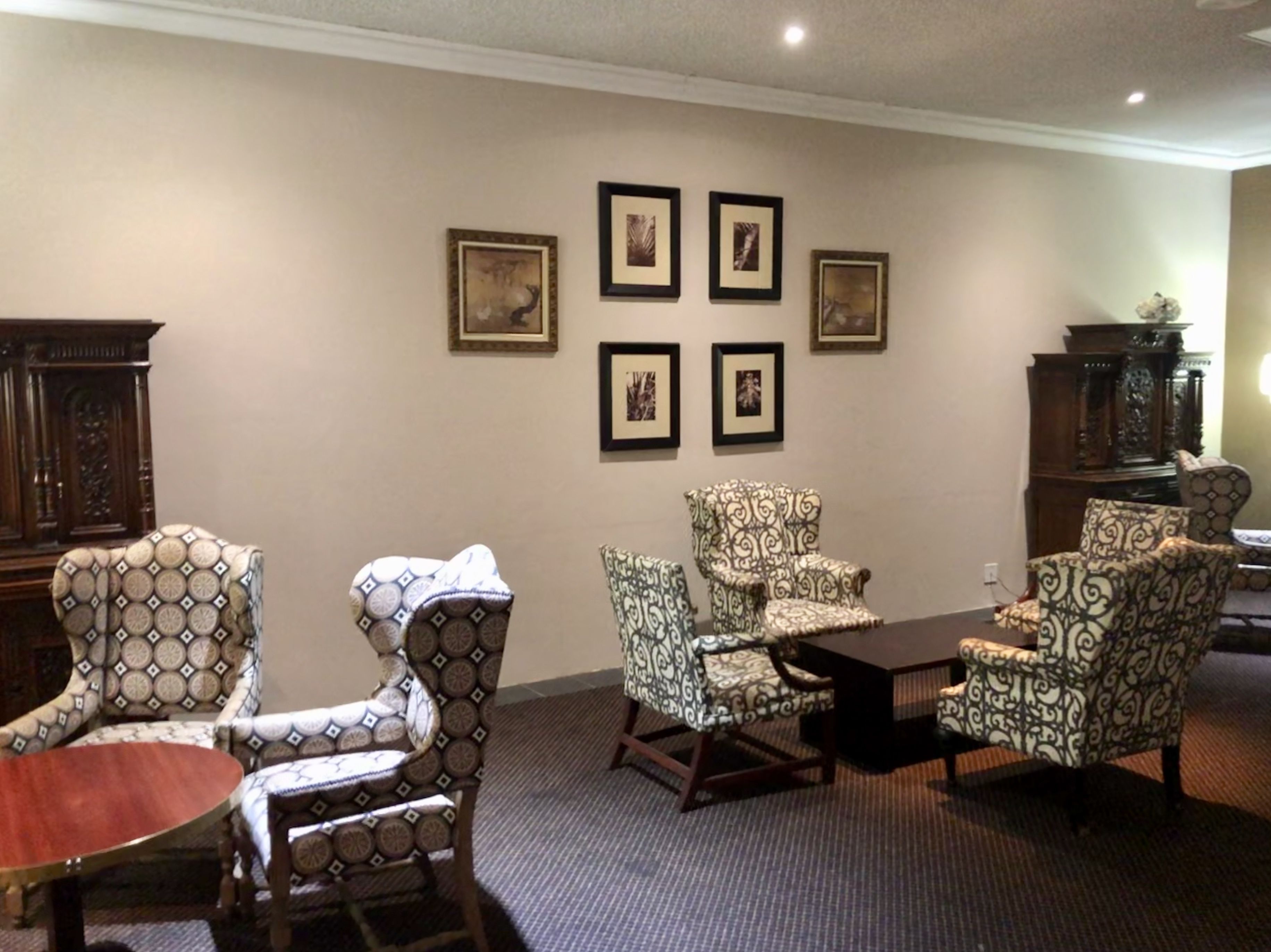 Un salon avec des fauteuils à motifs, une table basse en bois et un meuble.