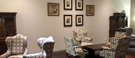 Uma sala de estar com poltronas estampadas, uma mesa de centro de madeira e um aparador.