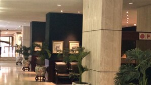 Un vestíbulo con piso pulido, zonas de estar y plantas en macetas.